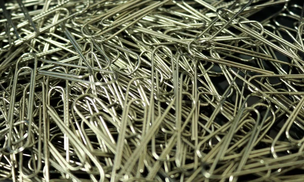 A pile of paper clips made of silver stainless steel, this tool is usually in the office