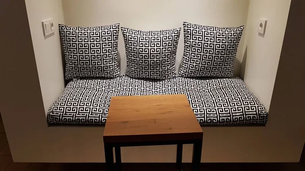 Three pillows on the sofa and a table