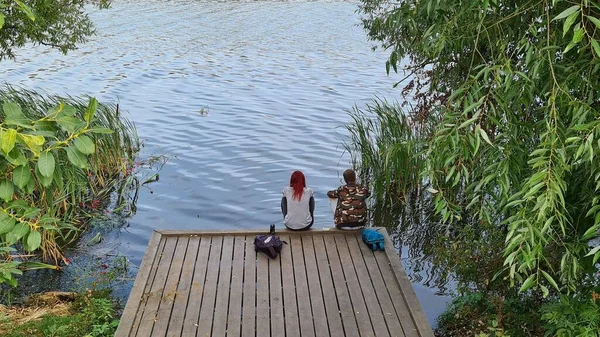 Çift nehir kıyısında ahşap bir platformda oturuyor..