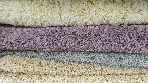 Farklı renkte ve yapılarda yığılmış halılar. 