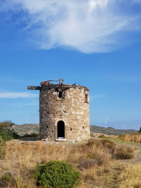 Terk edilmiş eski taş değirmenleri, güneşli bir yaz akşamında bir tarladaki rüzgar değirmenleri, sonsuz tarlalar, turizm ve dinlenme konsepti.