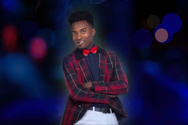 Dans pistindeki adam kareli ceketli mavi ışıklar arka plandaki bokeh daireler çapraz kollar ve dumanda gururlu papyon