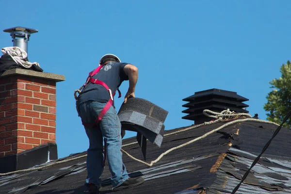 construction man roofer working on roof removing shingles repair