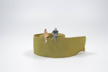 Beyaz arka planda kurdele üzerinde oturan insan figürleri