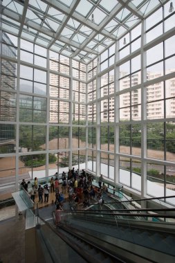 Binanın içinde büyük pencereli yürüyen merdivenler olan insanlar