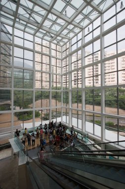 Binanın içinde büyük pencereli yürüyen merdivenler olan insanlar