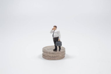 Bozuk paraların üzerinde telefonla duran küçük işadamı figürü