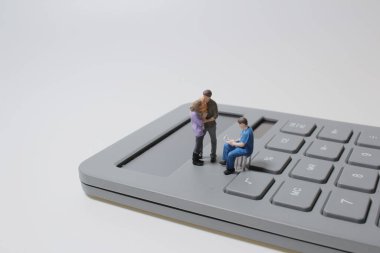 Hesap makinesindeki küçük insan figürleri beyaz arkaplanda