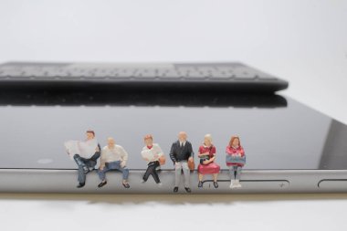 Dijital tablette oturan insanların mini figürleri