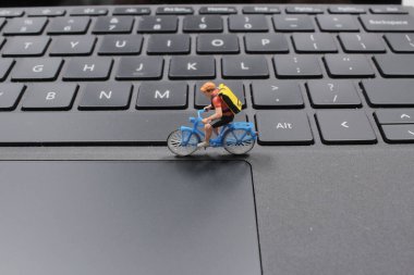 Dizüstü bilgisayarda bisiklete binen küçük adam figürü