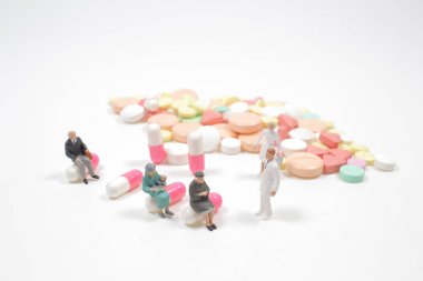 Beyaz arka planda hapları olan insanların mini figürleri