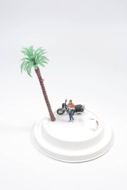 Mini adam, motosikletle kağıt bardak kapağında duruyor.