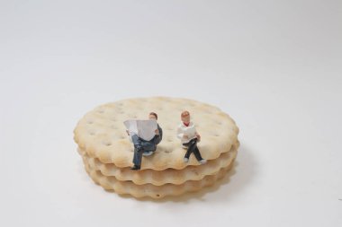 Bisküvinin üzerinde oturan bir adamın minyatür figürü.
