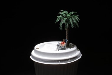 Kâğıt bardakta ağaçla dinlenen adam.