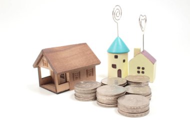 Mülkiyet ve finansal konsept olarak kullanılan madeni paraların üzerindeki minyatür renkli ev