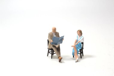 Minyatür insanlar sandalyeye oturur.