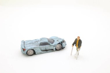 Minyatür insanlar kırık bacaklı adam bandajlı hasta oyuncak araba enkazı ile koltuk değneğiyle yürüyor