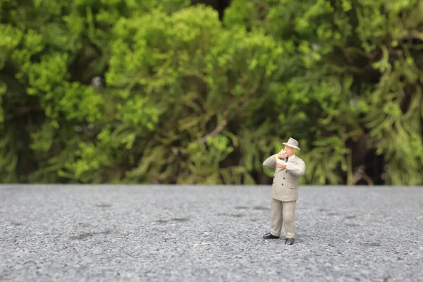 Minyatür iş adamı açık havada sigara içiyor. 