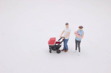 the mini of Mother and father walking outdoors and pushing baby in pram