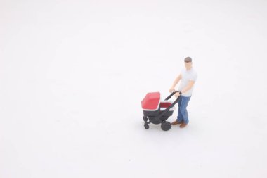 Minyatür insan figürü bebek arabasıyla yürüyor. 