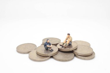 Bozuk para yığınının içinde oturan mini figür. 