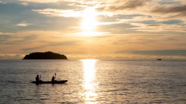 Kayakers paddling on the sea at sunset at Koh Chang island in Thailand