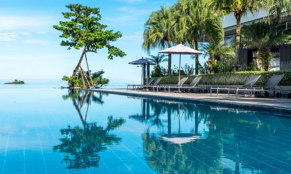 Infinity pool at a tropical resort reflecting the sky and clouds