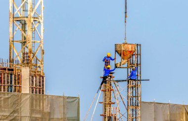 İşçiler yüksek katlı bir şantiyeye beton döküyorlar
