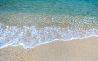 Temiz su ve yumuşak dalgalar Tayland 'da tropikal bir sahilde kırılıyor.