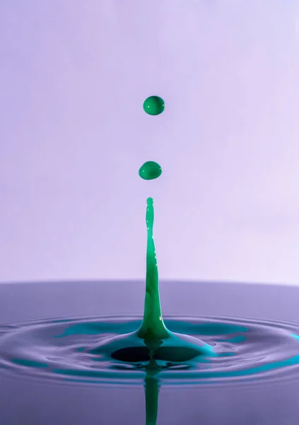 Close Green Colored Water Drop Splashing Surface Purple Background — Stok Foto