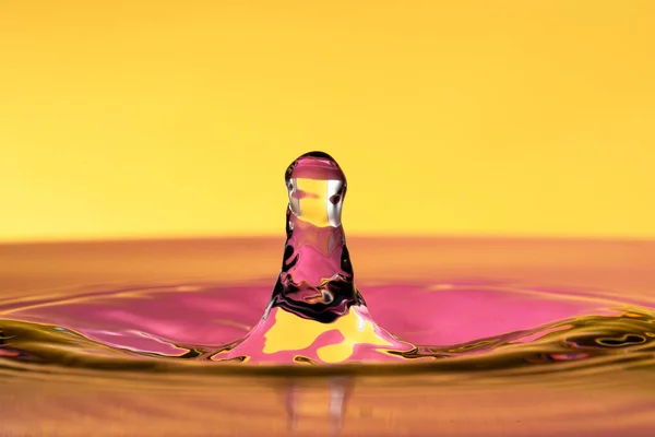 Water drop splash isolated on yellow background.