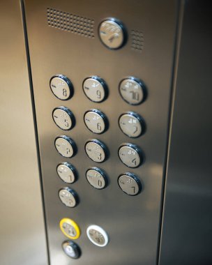 Seçili odaklı asansör düğmeleri. Yansıtıcı metal asansörün içinde dikey yakın çekim fotoğrafı.