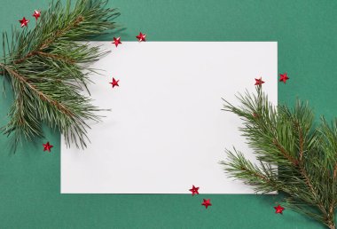 Ağaçların dalları ve yeşil arkaplan üzerine boş kağıt