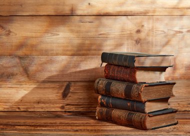 Stack of old books on wooden background clipart