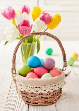 Sepet renkli Paskalya yumurtaları ve lalelerle dolu.