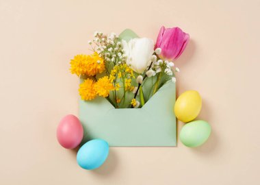 Paskalya yumurtaları ve bahar çiçekleri bir zarfın içinde.