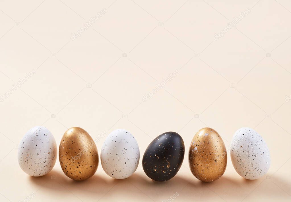Golden,white and black eggs on beige background