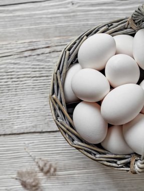 Tahta arka planda beyaz çiftlik yumurtaları olan sepet.