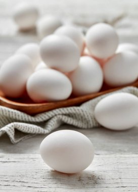 Tahta tepside beyaz yumurtalar, beyaz ahşap arka plan.