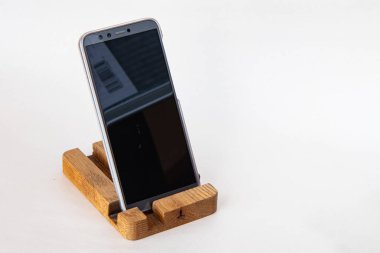 El yapımı ahşap stantta akıllı telefon, beyaz arka planda izole.