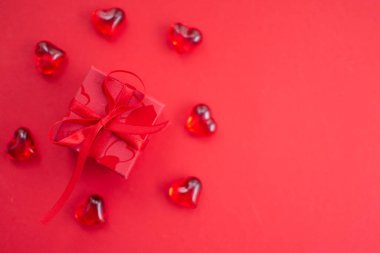 A red giftbox surrounded by red hearts