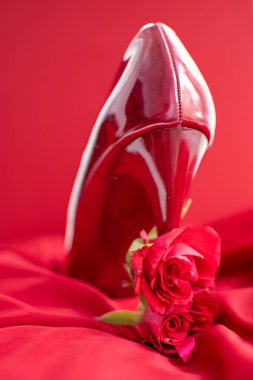 Red hot high heel shoes on a red satin background with red roses