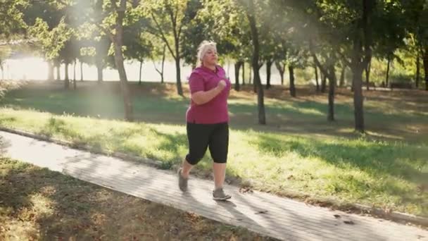 Товста жінка біжить в парку — стокове відео