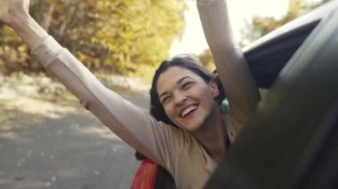 Arabanın camından sarkan neşeli kadın.