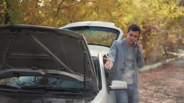 Человек рядом со сломанной машиной зовет на помощь — стоковое видео
