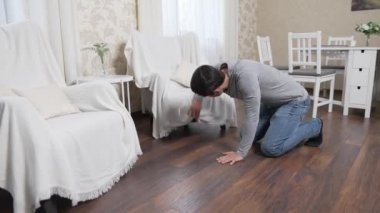 Sandalyelerin altında bir şey arayan adam.