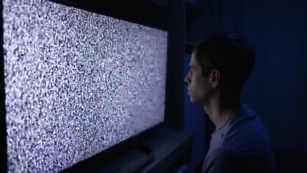 Мужчина смотрит телеканал с зерном — стоковое видео