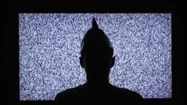 TV karşısında folyo şapka takan bir adamın silüeti.