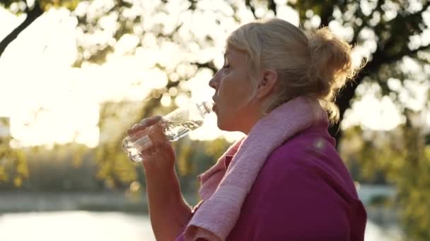 Жирная женщина пьет воду после занятий спортом — стоковое видео