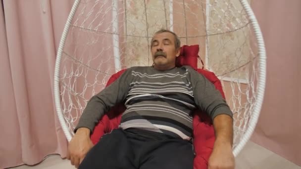 Divertido maduro hombre balanceo en un columpio silla — Vídeos de Stock
